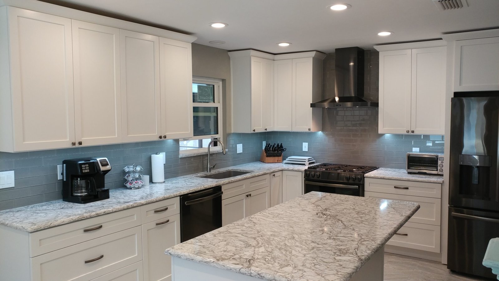 Open-concept contemporary white kitchen cabinets with quartz island in Kitchener, Ontario